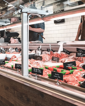 Close-up of a tender Glanmire Murray Greys beef slice held on a fork against a black background.