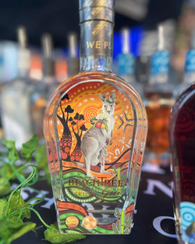 Beachtree Ocean Blue gin liqueur bottle displayed beside a koala holding a purple cocktail at a beac