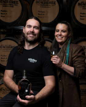 Beachtree Ocean Blue gin liqueur bottle displayed beside a koala holding a purple cocktail at a beac