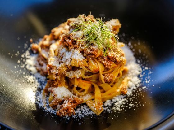 Plate of tagliatelle pasta topped with Moredough Kitchens’ rich Bolognese sauce, garnished with chee