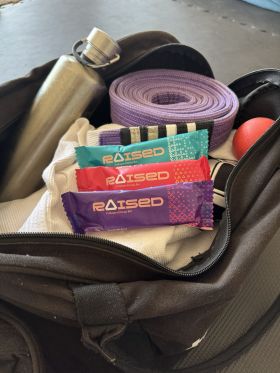 Raised collagen protein bars in Salted Caramel, Chocolate Almond and Açaí flavours on wooden table