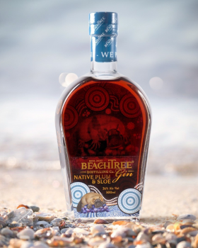 Beachtree Ocean Blue gin liqueur bottle displayed beside a koala holding a purple cocktail at a beac