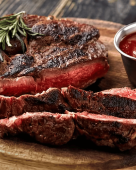 Close-up of a tender Glanmire Murray Greys beef slice held on a fork against a black background.