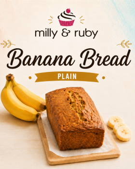 Three loaves of Milly & Ruby banana bread arranged on a marble surface with fresh bananas, a mango,