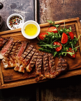 Close-up of a tender Glanmire Murray Greys beef slice held on a fork against a black background.