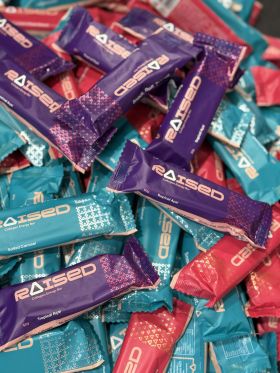 Raised collagen protein bars in Salted Caramel, Chocolate Almond and Açaí flavours on wooden table