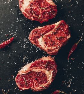 Raw beef cuts including steaks and ribs on a board with herbs and spices, representing Melbourne Mea