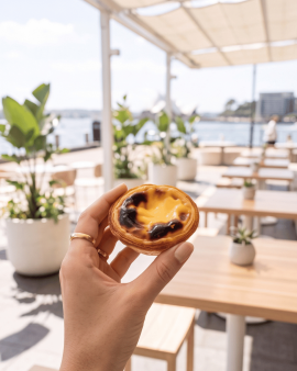 Portuguese custard tarts with golden flaky pastry and caramelised tops, served with cinnamon sticks,