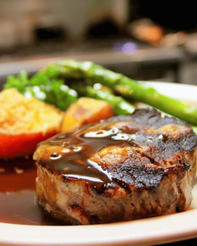 Close-up of a tender Glanmire Murray Greys beef slice held on a fork against a black background.