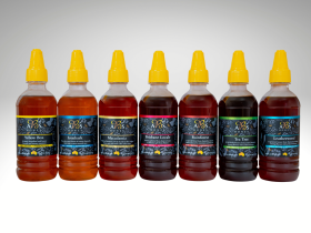 Assorted sizes of AB’s raw Australian honey in plastic tubs with yellow and white lids displayed on